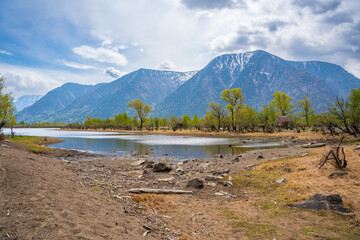 Kyrsai bay on southern shore of Teletskoye lake with forest and towering mountains. Pristine natural landscape in Altai Russia wilderness