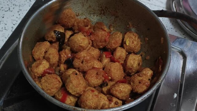 Soya chunks cooking in a pan with spices and vegetables. Protein-rich vegetarian food preparation captured during home-style Indian cooking.