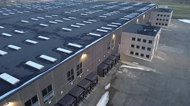 Modern transport center featuring multiple loading docks and an adjacent office building. The clean industrial architecture and organized logistics layout highlight efficiency