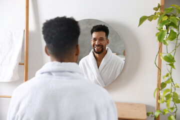 Fototapeta premium Handsome man looking at himself in mirror at home