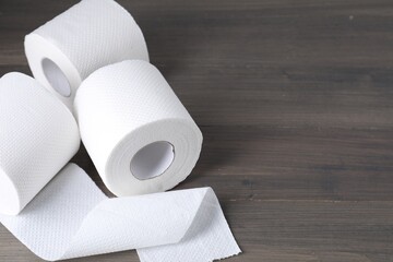 Rolls of toilet paper on wooden table, closeup. Space for text