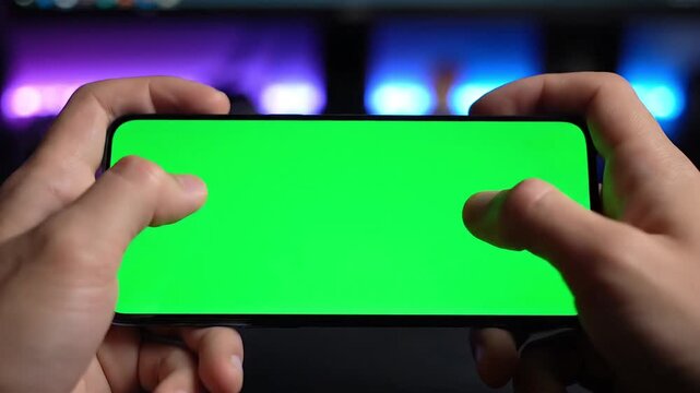 A person holding a smartphone with a green screen in front of a colorful video background.