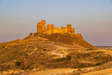 Obraz premium Castillo de Montearagon ruins on a golden hill at sunset