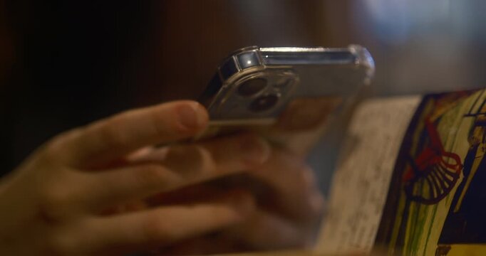 Cinematic close up of a teenager&rsquo;s hand holding a smartphone, actively typing messages and scrolling on the screen. smartphone brand Moscow Russia 01.05.2026