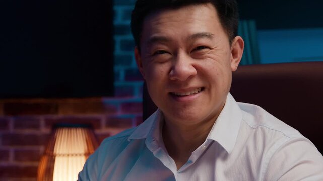 Portrait smiling Asian business man looking at camera working laptop posing in evening office cheerful Korean businessman with computer work smile headshot Japanese Chinese male at night workplace