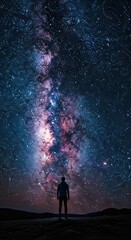 Obraz premium Vast Milky Way galaxy stretching across a dark night sky with a solitary figure