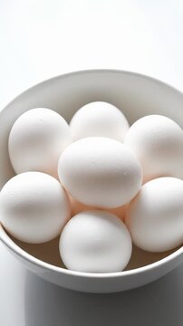 Fresh white eggs in bowl. Perfect ingredients for cooking and baking. Food preparation concept for healthy meal. Vertical arrangement highlights freshness and simplicity.