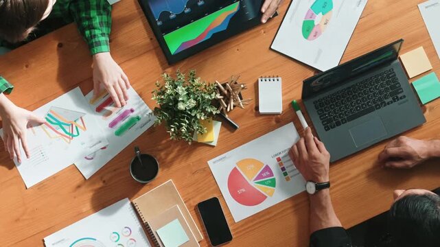 Top view of diverse businesspeople discuss about financial plan at meeting while looking at stock market statistic and explain marketing idea at meeting room. Creative startup concept. Convocation.