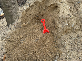 Red shovel in a pile of sand- Fun at the beach or sandbox play for children with summer adventure theme
