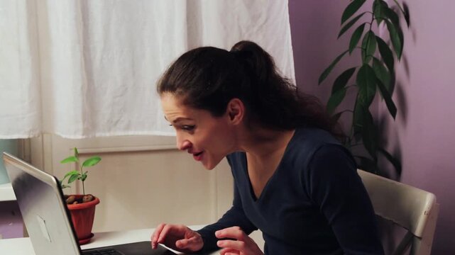 Happy success laughing business woman working at the laptop with emotional beauty face sitting at the table. Female looking in the screen of notebook