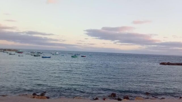 A beach, rocks and boats are on the opposite side of Al-Kour Island (Miami Island). A great view of the Mediterranean Sea and the sky is on the other side of the island. The view is near the sunrise.