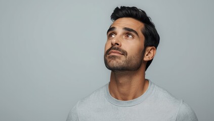 Obraz premium Image of an attractive, accomplished man in a gray sweater, gazing sideways against a plain backdrop, contemplating decisions and goals