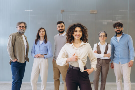 Diverse business team smiling at camera, showing unity and professionalism in a modern office environment