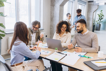 Fototapeta premium Diverse startup team discussing sustainable energy project, collaborating in modern office, analyzing wind power models