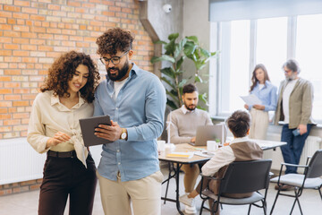 Diverse business team collaborating in a modern office, using technology for discussion and...