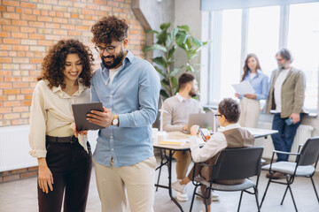 Diverse business team collaborating using digital tablet in a modern office space, sharing ideas and working together