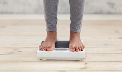 Closeup of young African American woman standing on scales indoors, checking her weight, cropped...