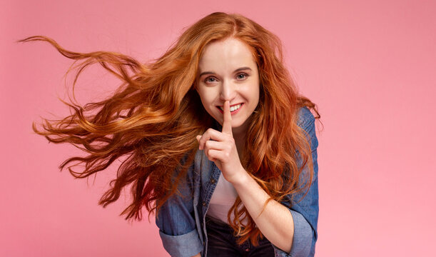 Women's secret. Mysterious teenage lady put finger on lips, showing silence sign, close up