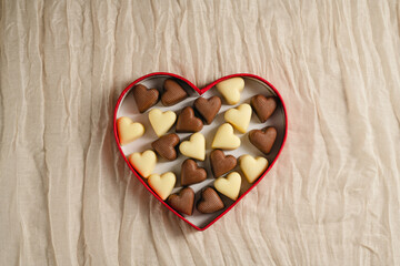 Valentine's Day chocolate candies in red heart shaped box on neutral background. Top view with copy space