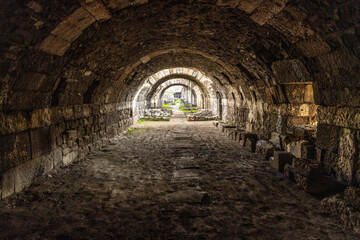 Fototapeta premium Ancient stone arches of the Agora of Smyrna in Izmir, Turkey. Perspective view inside the ruins of a Roman basement with historic masonry and pillars during a bright day