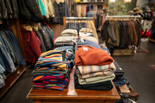 Interior of trendy fashionable clothing vintage store with various assortment of clothes and accessories displayed on hangers and table, fancy apparel showcased in old fashioned second hand shop