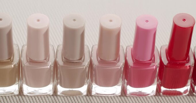 Colorful palette of nail polish bottles in a row with different shades from nude to red, representing a choice of beauty products for manicure and pedicure in a cosmetic salon or store