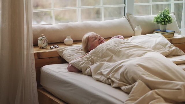 Happy senior woman waking up and stretching in the morning after healthy sleep