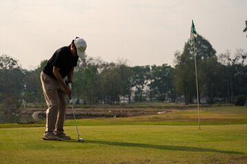 Obraz premium Golfer putting on green near hole with flag, focus and precision moment. Outdoor golf practice, concentration, skill, competition, and active lifestyle. golfer, putting, putt, flag, golf course, sport