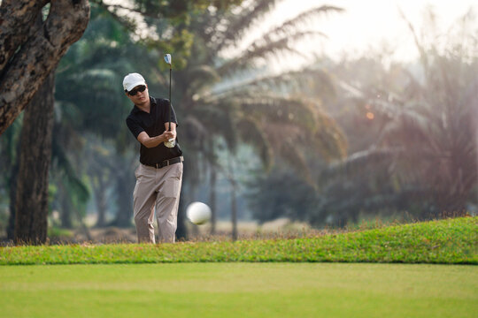 Golfer hitting chip shot near green with ball in motion. Outdoor golf action, short game skill, precision and control, practice, competition and lifestyle. golf, golfer, swing, golf course, sport