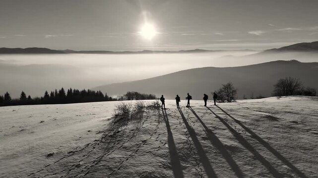 Black and white contrasty drone shot of. hikers on top of hill enjoying afternoon sun. Misty valley with smog. Winter air pollution problem. 