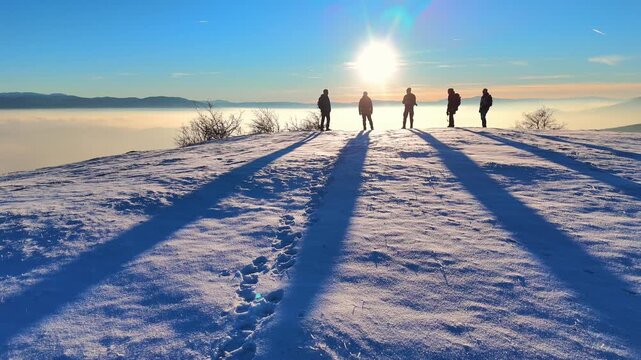 Silhouette of a hikers on top of hill. Winter outdoor sports activity. 