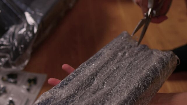 Removing packaging from furniture. Carefully stripping protective materials from seat. Closeup view of carefully removing protective coverings from furniture piece indoors