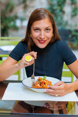 Fpv view of a woman enjoying a plate of pasta and smiling