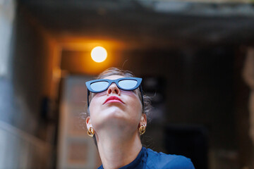 Woman looks up while wearing black sunglasses in an urban setting