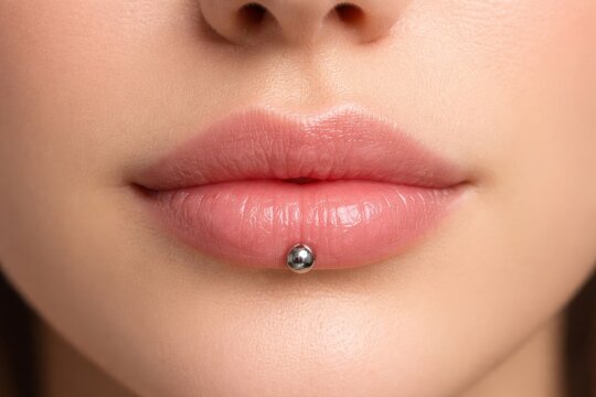 Woman face closeup showing lower lip with piercing jewelry. Body modification and aesthetic enhancement concept for beauty salon.