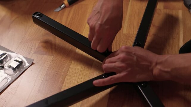 Hands assemble chair. Calm living room scene showing detailed furniture assembly process. Detailed tutorial on attaching casters and parts to chair base with precise technique
