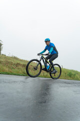 Obraz premium Cyclist riding mountain bike on wet road with fog