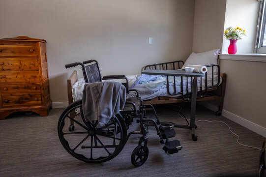 An empty room in a hospital or assisted living facility with an empty bed and empty wheelchair. 