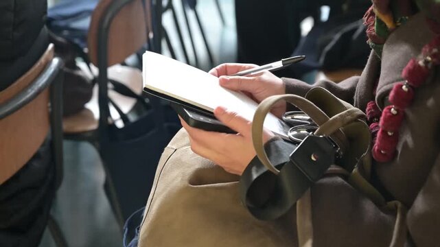 donna in affare prende appunti su di un blocco note durante una conferenza di lavoro