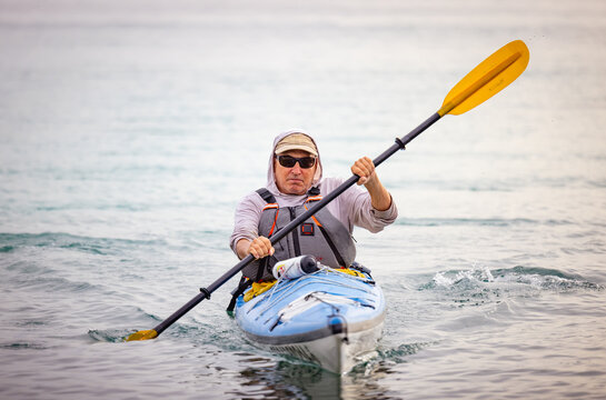 Horizontal image of middle-aged man coming toward viewer in a sea kayak.  