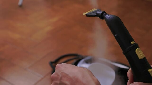 Household brushes examined closely, Two brushes analyzed in indoor setting, Person holding two black brushes inspecting bristle arrangement for household cleaning purposes
