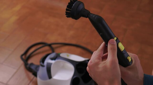 Household brushes examined closely, Two brushes analyzed in indoor setting, Person holding two black brushes inspecting bristle arrangement for household cleaning purposes