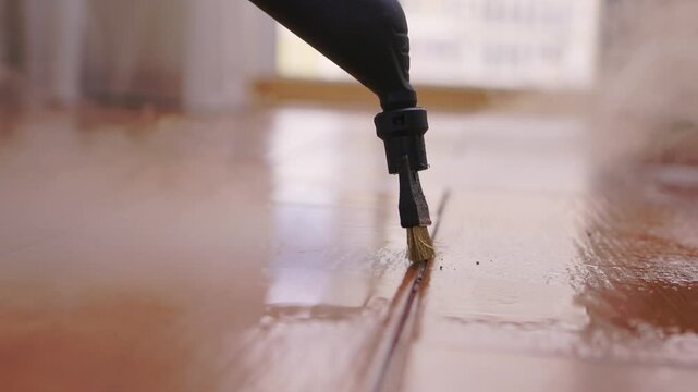 Floor cleaning detail. Technician delicately removing dirt from shiny floor grout lines. Modern apartment floor restoration with precise nozzle and softening vapor techniques