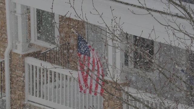 American Flag During Winter Storm Gianna. Strong Snow Blizzard in Winter, Greenville, South Carolina. Blizzard Strong Wind And Heavy Snow Lash Town. American Flag Heavy Snowstorm in Residential Area.