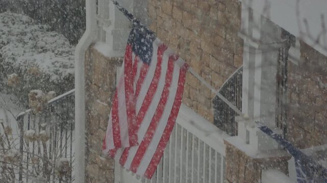 American Flag During Winter Storm Gianna. Strong Snow Blizzard in Winter, Greenville, South Carolina. Blizzard Strong Wind And Heavy Snow Lash Town. American Flag Heavy Snowstorm in Residential Area.