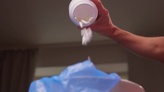 Responsible medication disposal in residential living space, An individual safely discards expired tablets from open containers into trash in living room setting