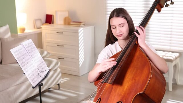 Teenage girl playing double bass at home