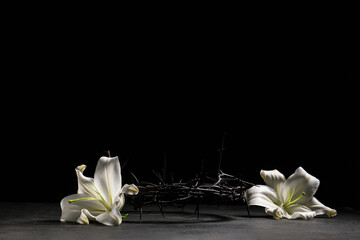 Crown of thorns with beautiful lily flowers on black background