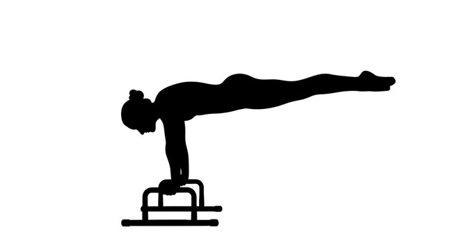 A gymnast performs a handstand on parallel bars in a sports arena with athletic equipment