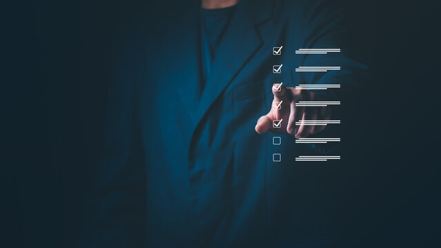 Businessman's hand touching a digital checklist on a virtual screen, Concept of task management, quality control, productivity, project planning, and completion of business goals or compliance